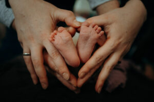 Babyfüße mit Händen als Herz geformt