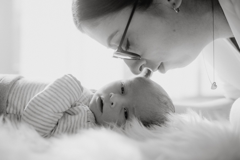 Neugeborenenes Baby mit Mutter vor Fenster fotografiert von Marc Feix Photography